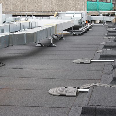 Felt roofing South East- Flat felt roofing system with rooftop plant supports and ventilation units on a commercial building.