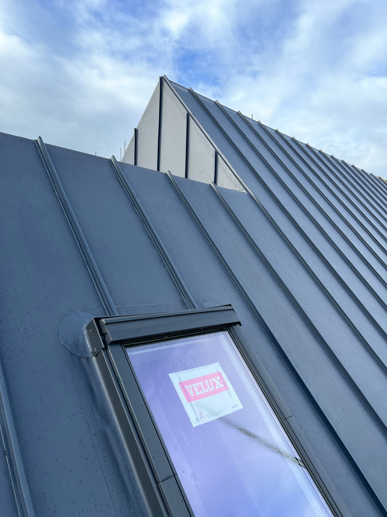 Standing seam Single ply roofing system with integrated skylight on a pitched roof residential building. AJ Lucas Roofing services in South East UK