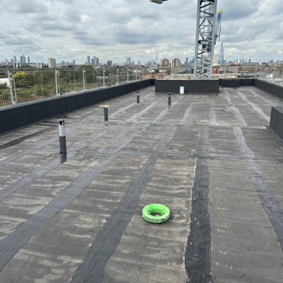 Hot melt roofing South East, installation on a high-rise commercial building with city skyline and crane visible.